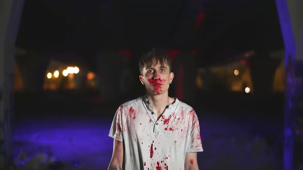 Crazy serial killer looks at camera with psycho face. Murderer at crime scene. alt