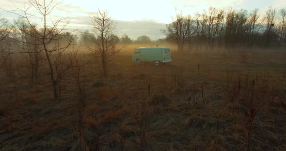 Road trip friends in hippie car. Aerial view of a retro van in fog.  alt