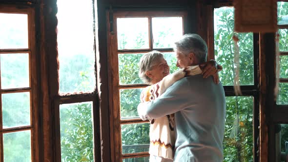 Happy senior couple smile and dance at home enjoying love and relationship together