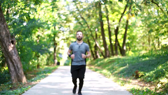 Sportsman jogging in forest, looking at smartwatch