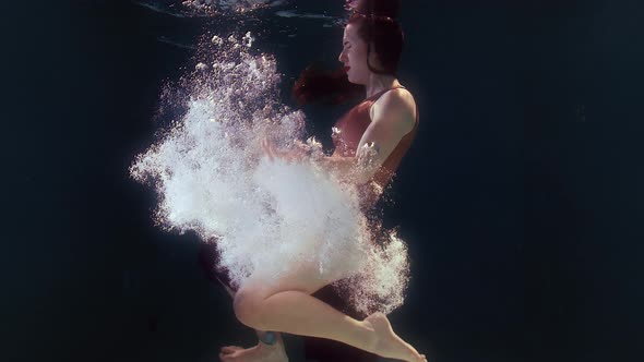 Woman in a Swimsuit and a Black Skirt Swims in the Water Waving Arms and Legs