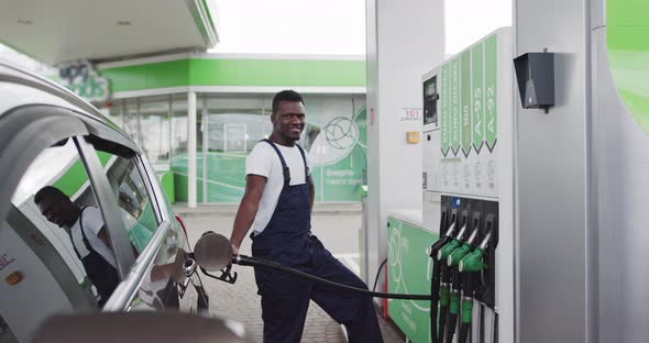 A Black African Refueling Worker Holds A Gun To Refuel A Car alt