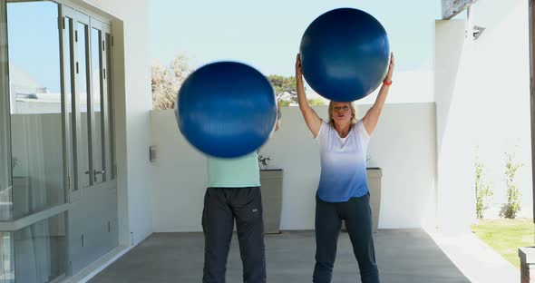 Senior couple exercising with exercise ball alt