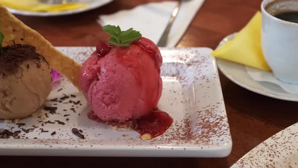 A portion of ice cream on a table in a cafe. Raspberry and Coffee Ice Cream.