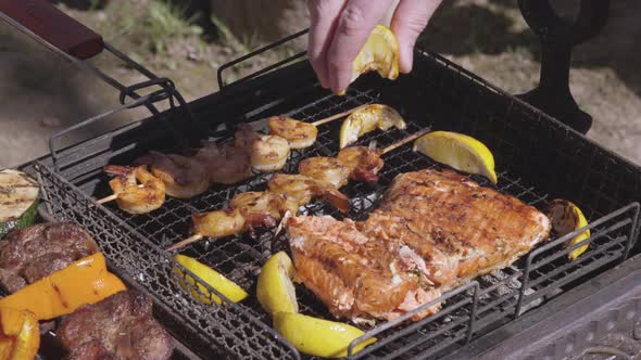 Close-up of a Hand Squeezing Lemon Juice on Grilled Trout and Shrimp