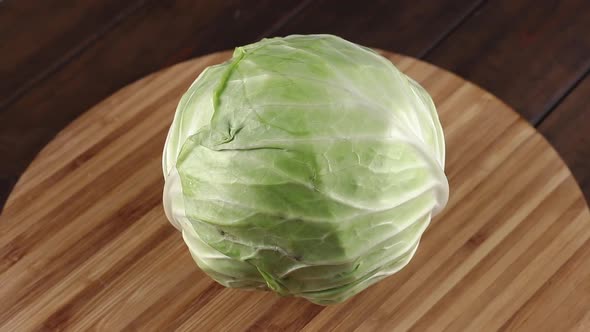 fresh green cabbage rotating close-up on a wooden table with cutting board