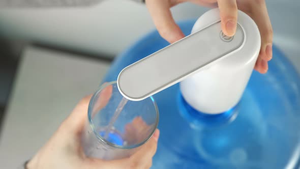 Woman's Hands Pour Water Into Glass From Automatic Water Cooler Closeup View