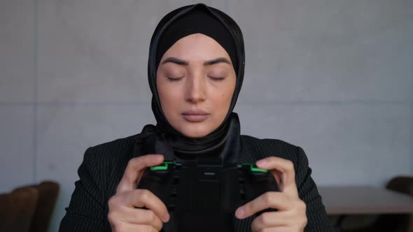 Young Muslim Woman in Hijab Playing Mobile Game in Cyberspace at Cafe Whit Device