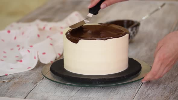 Closeup of a Pastry Chef Pouring Liquid Chocolate on a White Cream Cake