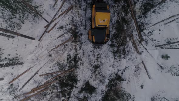 Top down Aerial view of Forest Forwarder stacks tree logs in the winter forest. 24 alt