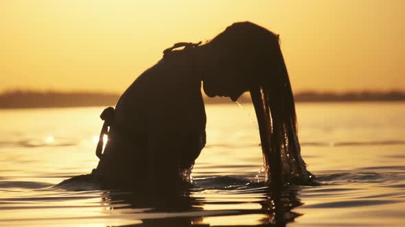 Silhouette of Woman Flipping Her Long Hair Back in Water. Slow Motion 240 Fps alt