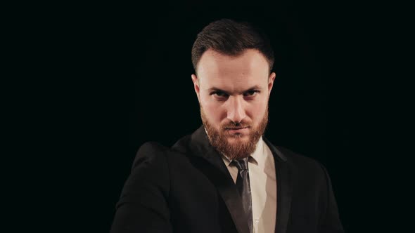 A Man in a Suit is Standing on Stage and Looking at the Camera alt