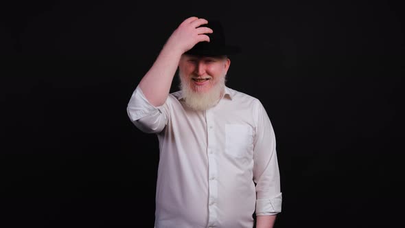 Bearded Albino Man in Casual Outfit Smiling and Taking a Hat Off. alt