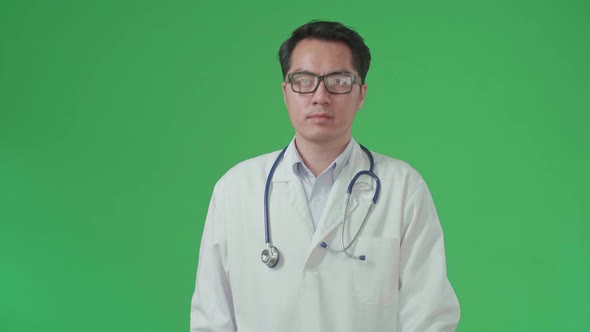 Asian Doctor With Stethoscope Wearing Glasses And White Coat Walking On Green Screen alt
