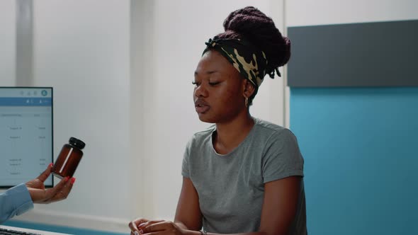 Close Up of Young Patient Receiving Bottle of Pills From Doctor alt