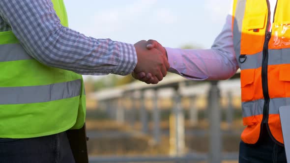 Two engineer handshake together on solar panel background alt