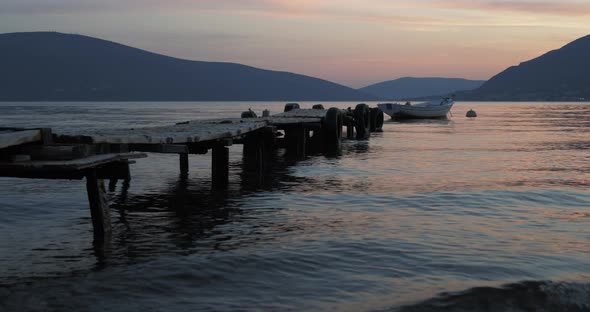 A Boat Tied To a Wooden Pier in the Sea in the Evening