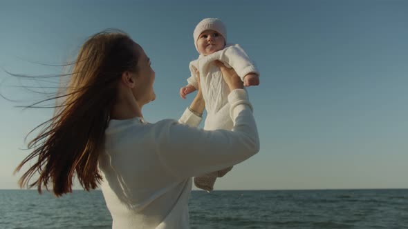 Mom Holds Her Daughter in Her Arms at the Sea