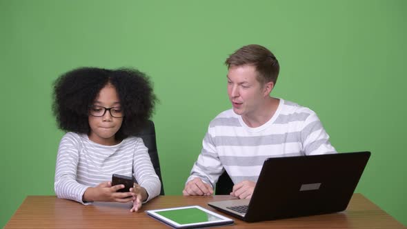 Young African Girl and Young Scandinavian Man Using Gadgets Together alt