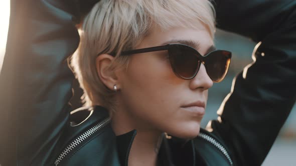Close Up of Joyful Young Woman with Bright Hair and Sunglasses Standing with Hands Over the Head alt