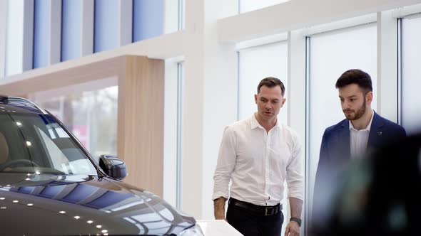 A Salesman Showing the New Car Model to a Client alt