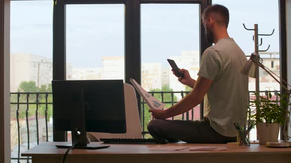 Entrepreneur Alone in the Office Looking at Charts and Graphs in Warm Sunset Light alt