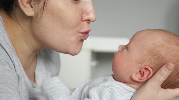 Mother Babbles with Newborn Baby Girl Holding in Arms alt