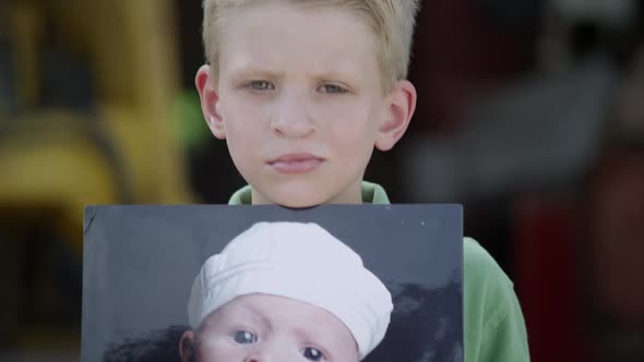 Slow motion from photo to boys face of him showing photo with cleft palate. alt