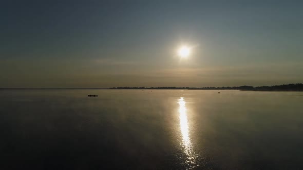 Silhouettes of Boats and Fishermen in Them on the Background of the Rising Sun