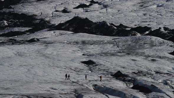 Long Shot of Tourist Groups Hiking Over Massive Glacier alt