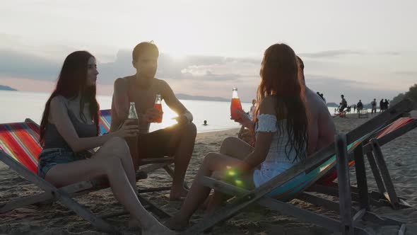 Silhouette of friends group having fun and drinking alcohol on beach. Vacations concept
