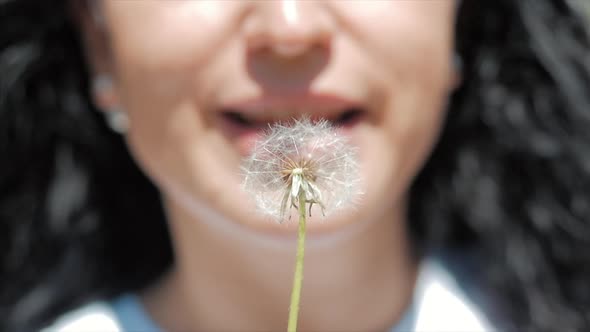 Slow Motion Close-Up Shot of Woman Carefree Blowing a Dandelion Outdoors on a Sunset alt