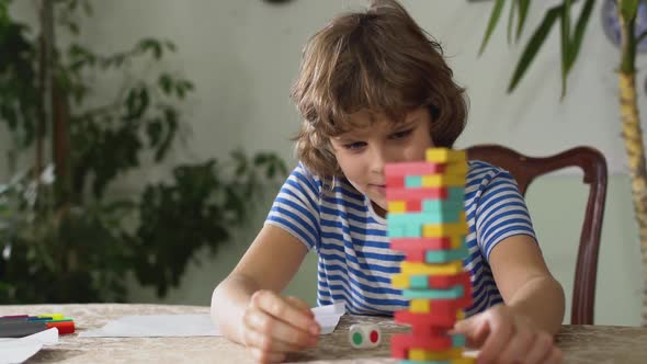 Small Adorable Cute Kid Sitting on the Table and Play Game Inside a Room. Boys Playing Jenga alt