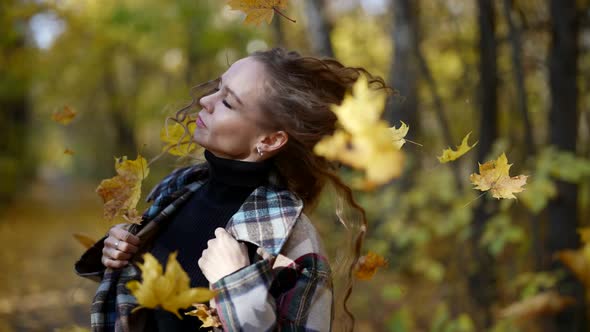 a Blonde with Long Hair and a Plaid Coat Walks Through the Autumn Park Through Falling Leaves and alt
