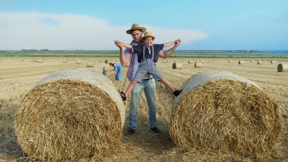 Parenting Pleasures, Father Spends Time Playing with Baby on Straw Bales in Field alt