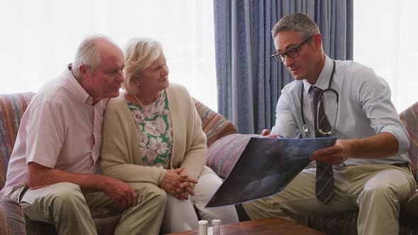 Senior couple talking with a doctor in retirement house alt
