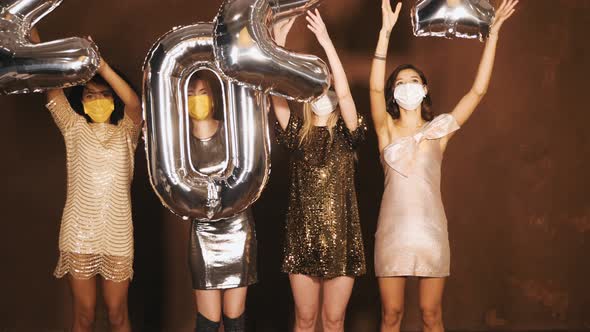 Four young international beautiful brunette women in trendy summer shiny dresses holding balloons alt