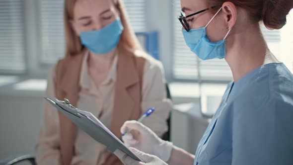 Woman at Doctor Appointment Signs Form After Examining Patient in Hospital Office alt