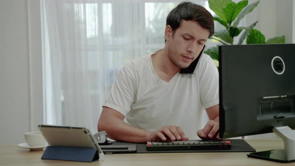 young man in casual clothes is stressed out of working from home on a desk with a computer and table