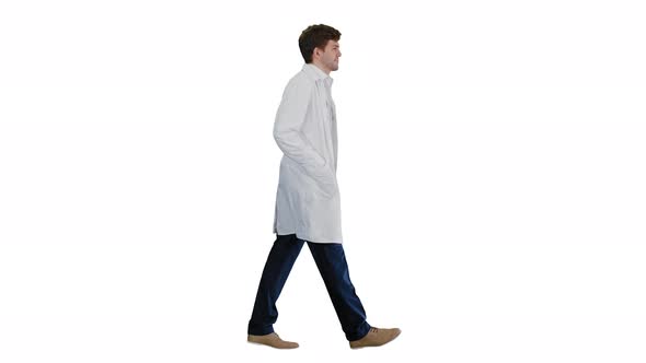 Male Doctor in White Coat Walking with Hands in Pockets Looking Straight Ahead on White Background alt