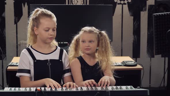 Two Girls Play the Synthesizer. Sister Teaches To Play a Musical Instrument.