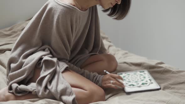 Pretty Brunette Is Watching Pictures in a Screen of Tablet in Bedroom alt