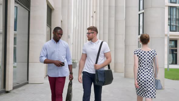 Multiethnic Business Colleagues Walking on Street and Discussing Details of Project alt