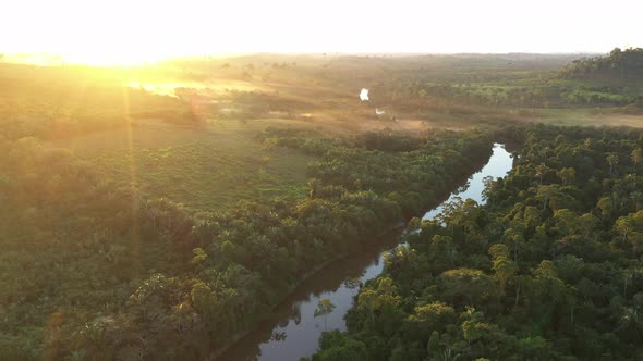 Drone Orbits A River, In The Middle Of The Amazon Rainforest, As The Sun Sets On The Horizon