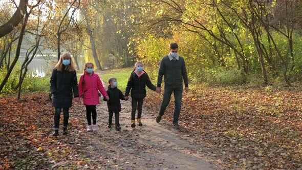 Family, parents with children in medical masks walk in the Park on an autumn day