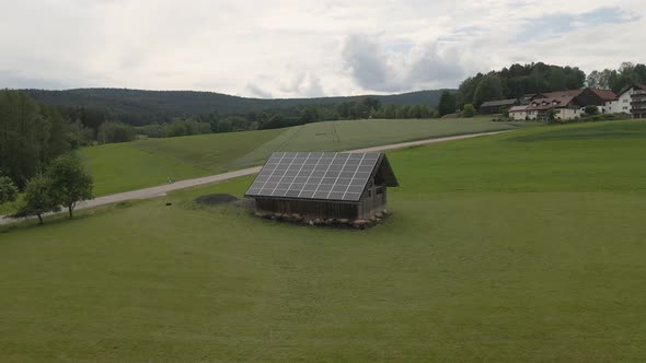 Sheep graze on a field near a barn with solar panels alt