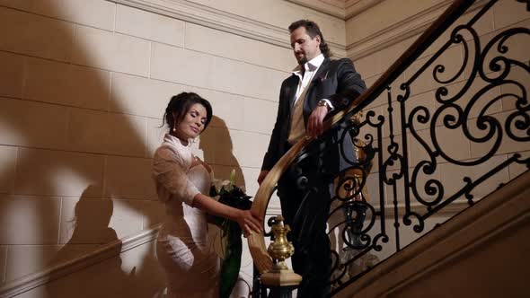 Romantic Loving Couple on Beautiful Staircase in Luxury Interior Hotel or Palace alt
