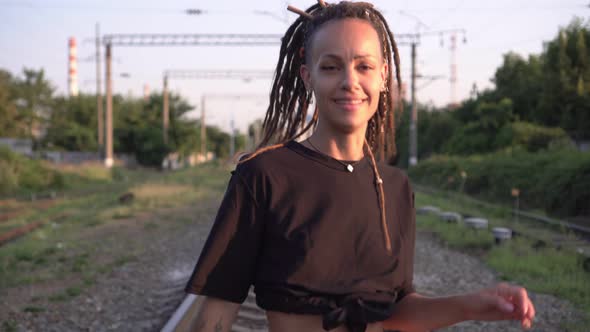 Young Stylish Woman Walks and Dances on the Railroad alt