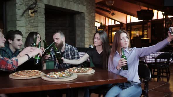 A Company of Friends Resting in a Pizzeria and Making Selfie on the Background of Pizza and Beer