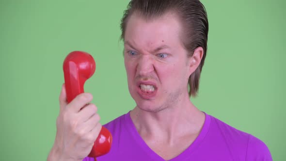 Face of Angry Young Man Shouting and Screaming at Old Telephone alt